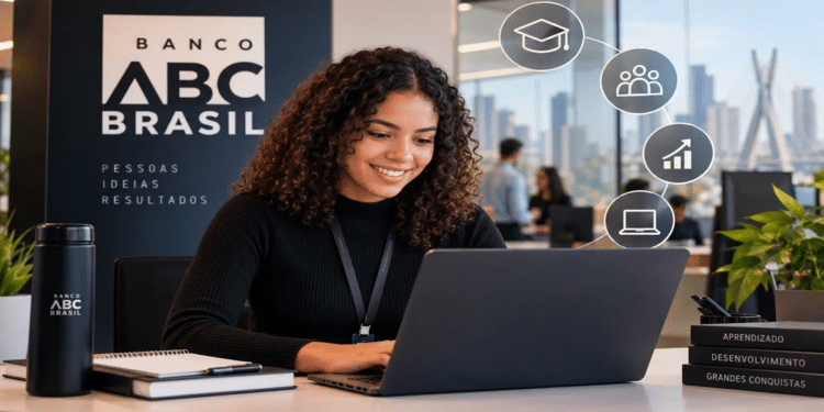 Mulher jovem de cabelos cacheados sorrindo, trabalhando em notebook no Banco ABC Brasil, livros com temas de desenvolvimento e ícones de crescimento ao fundo, simbolizando as inscrições para o estágio Banco ABC Brasil.