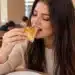 Mulher comendo esfirra em padaria aconchegante.