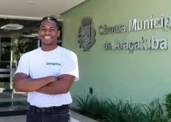 Estagiário da Câmara Municipal de Araçatuba sorri em frente à sede.