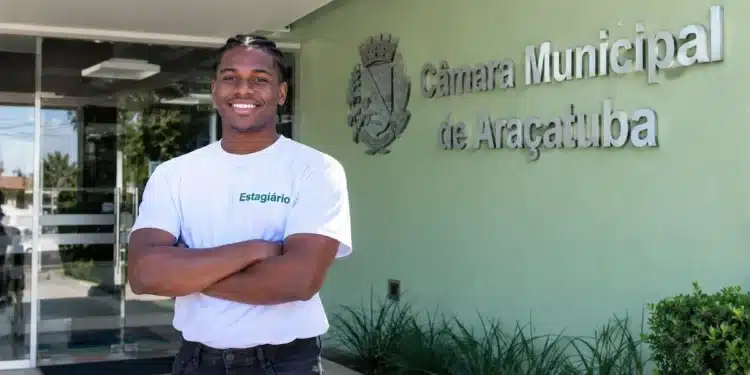 Estagiário da Câmara Municipal de Araçatuba sorri em frente à sede.