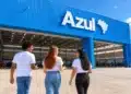 Três jovens conversam em frente ao hangar da Azul em um dia ensolarado.