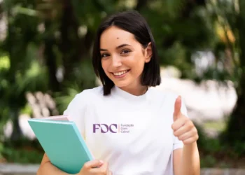 Estudante da Fundação Dom Cabral sorrindo e fazendo positivo.