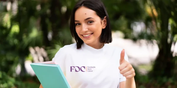 Estudante da Fundação Dom Cabral sorrindo e fazendo positivo.
