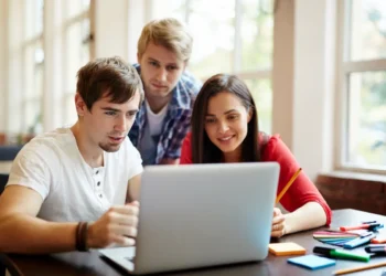 Jovens colaboram em projeto digital estudantil em ambiente iluminado.