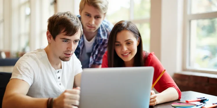 Jovens colaboram em projeto digital estudantil em ambiente iluminado.