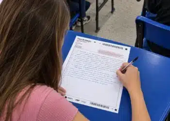 Estudante escrevendo a redação do Enem na folha de redação durante a prova.