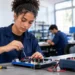 Estudante de curso técnico utiliza uma chave de precisão para trabalhar em uma placa eletrônica em laboratório.