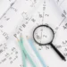 Equações físicas e lupa em análise de cálculos matemáticos.
