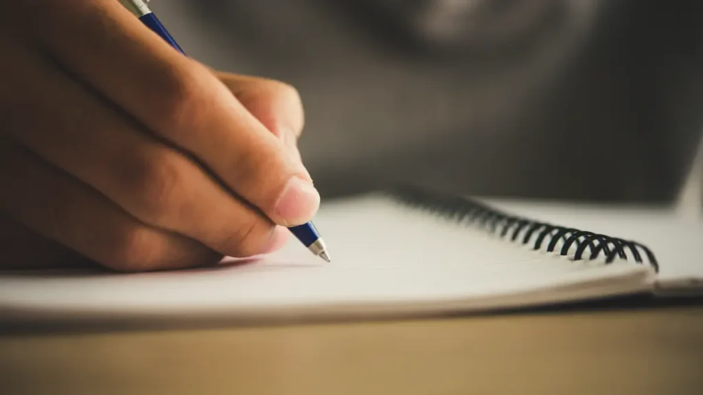 Mão escrevendo em caderno.