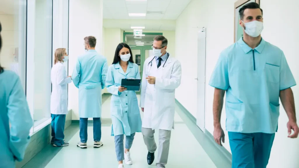Profissionais de saúde em corredor de hospital durante atendimento.