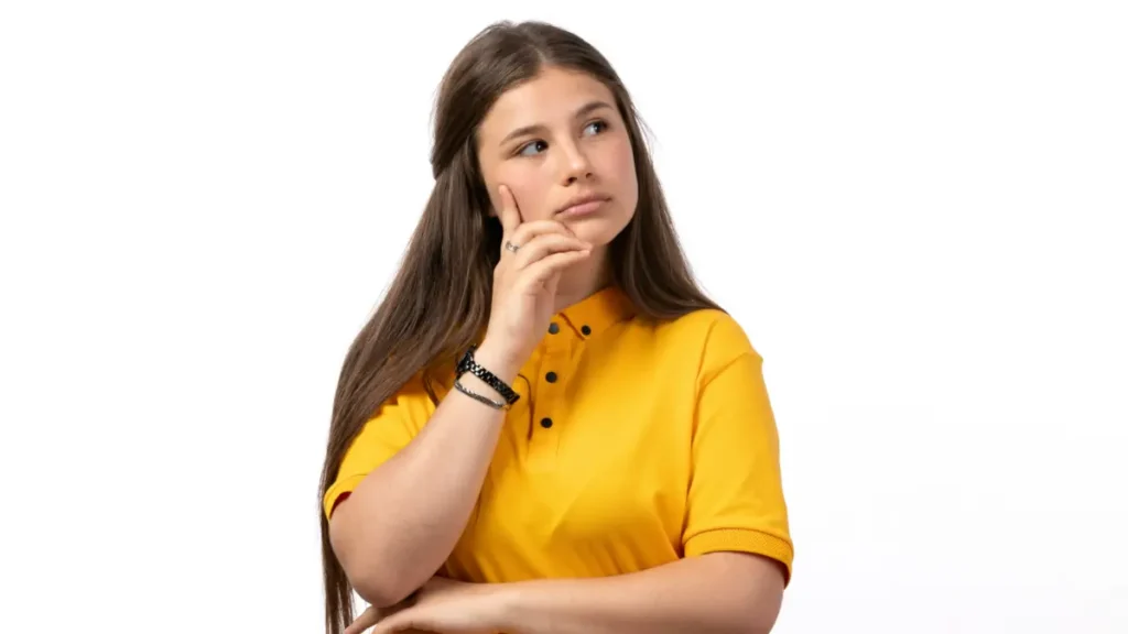 Jovem pensativa com camisa amarela em fundo branco.