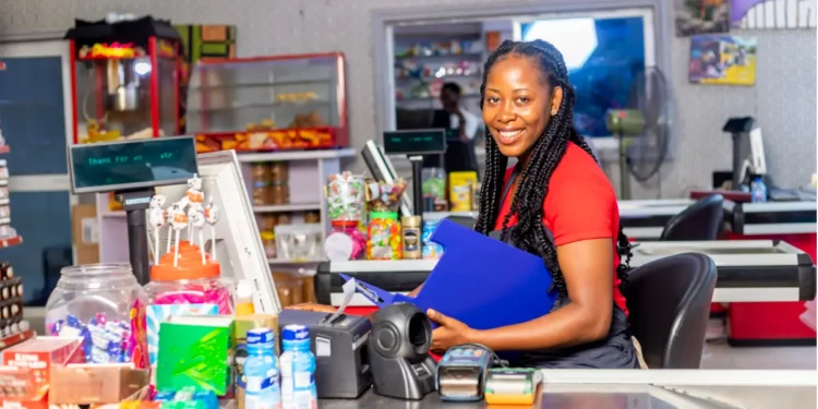 Atendente sorridente em caixa de mercado moderno com doces e produtos.