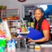 Atendente sorridente em caixa de mercado moderno com doces e produtos.
