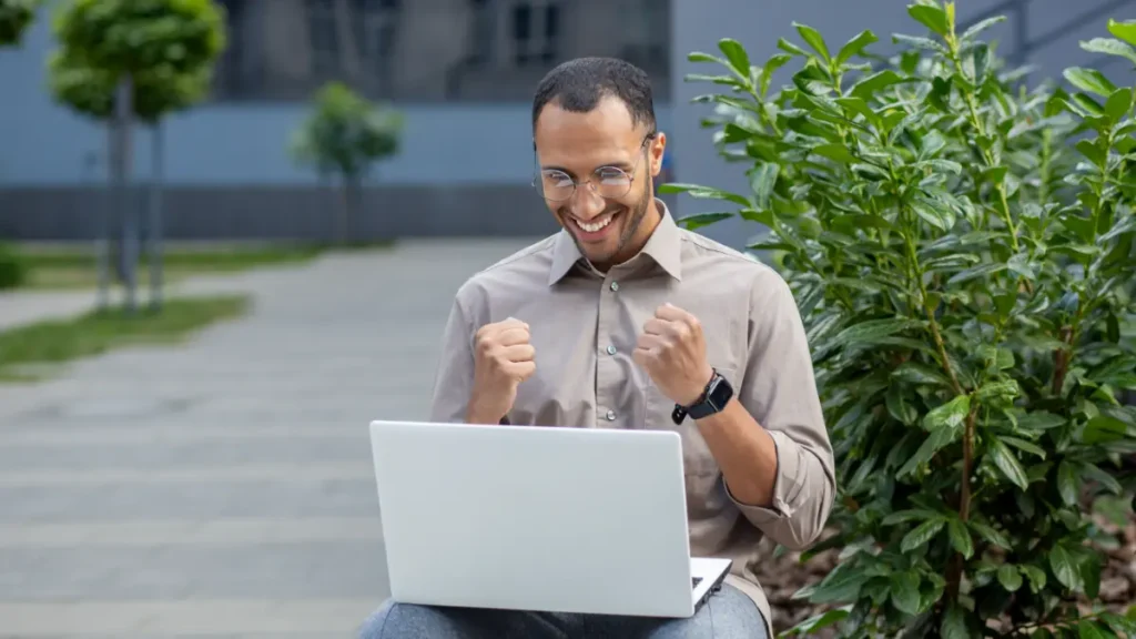 Homem olhando para notebook contente ao concluir sua inscrição na seleção de pós-graduação do IFSP.