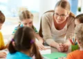 Professora interagindo com crianças em atividade escolar.