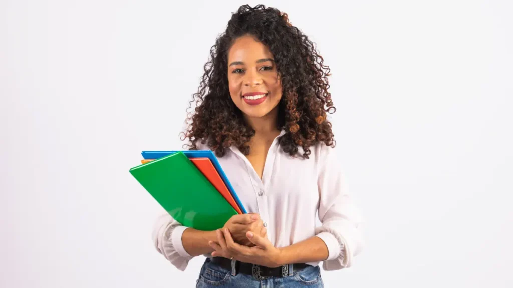 Jovem sorridente segura pastas coloridas com expressão acolhedora.