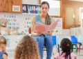 Professora lê livro para crianças em sala de aula infantil.