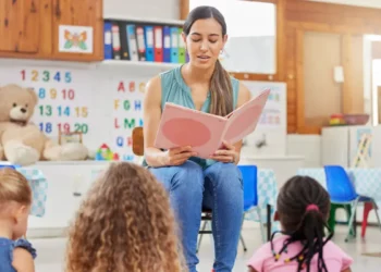 Professora lê livro para crianças em sala de aula infantil.