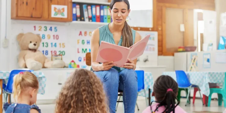 Professora lê livro para crianças em sala de aula infantil.
