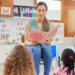 Professora lê livro para crianças em sala de aula infantil.
