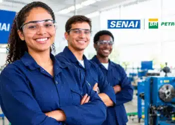 Três jovens sorrindo em uma oficina industrial, com uniformes azuis e logotipos do SENAI e da Petrobras.