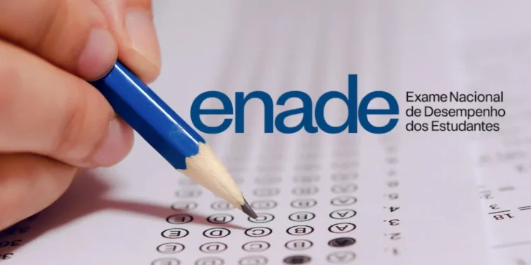 Mão preenche questão de múltipla escolha de prova do Enade com lápis azul ao lado do logo do exame.