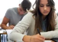 Jovens concentrados realizando prova em sala de aula.