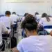 Alunos fazendo prova em sala de aula.