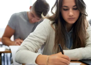 Jovens concentrados realizando prova em sala de aula.