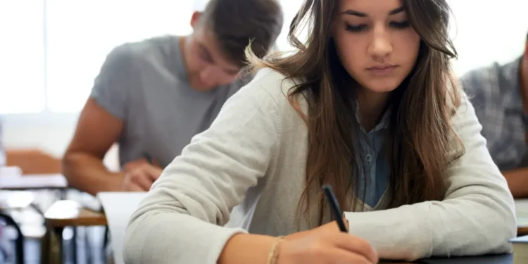 Jovens concentrados realizando prova em sala de aula.