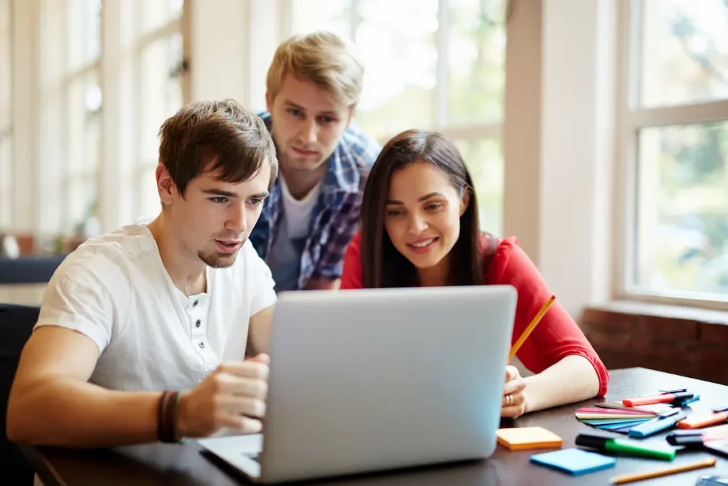 Grupo de jovens estudando juntos em frente ao notebook.