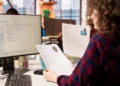 Análise de currículos por recrutadora em ambiente de escritório moderno.