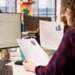 Análise de currículos por recrutadora em ambiente de escritório moderno.