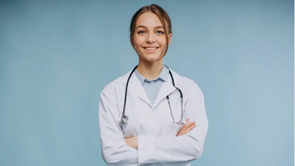Médica sorridente com jaleco e estetoscópio em fundo azul.