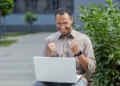 Homem feliz comemora inscrição em especialização da UFGD ao ar livre.