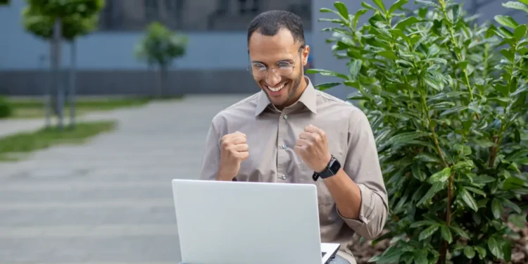 Homem feliz comemora inscrição em especialização da UFGD ao ar livre.