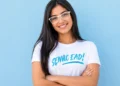 Estudante sorrindo para a câmera com óculos brancos e camiseta do Senac EAD.
