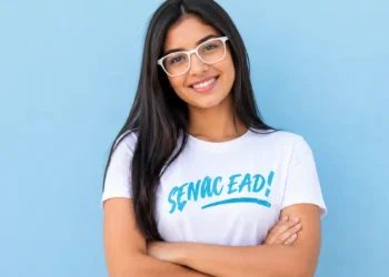 Estudante sorrindo para a câmera com óculos brancos e camiseta do Senac EAD.
