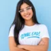 Estudante sorrindo para a câmera com óculos brancos e camiseta do Senac EAD.