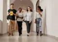 Jovens estudantes caminhando sorridentes no corredor de faculdade.