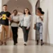 Jovens estudantes caminhando sorridentes no corredor de faculdade.