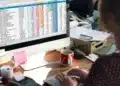 Pessoa analisando planilha colorida de orçamento em ambiente de escritório.