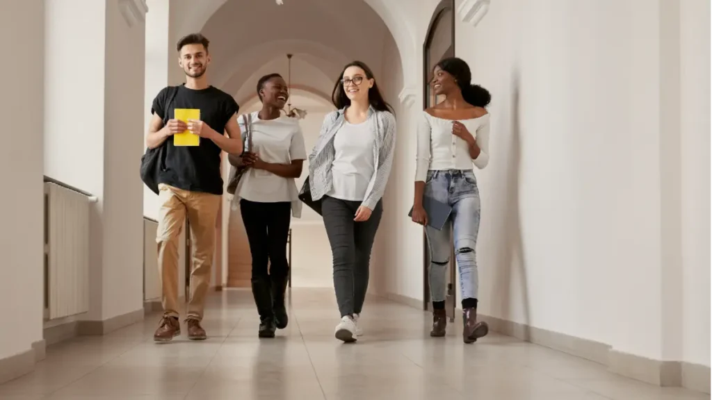Estudantes caminhando em corredor de faculdade.