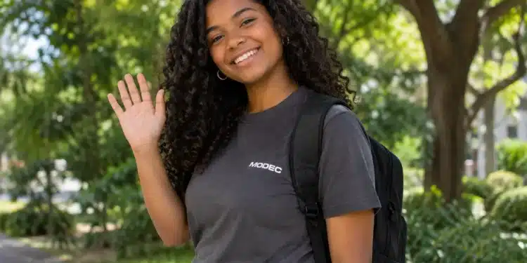 Jovem sorrindo e acenando, com camiseta da MODEC e mochila nas costas.