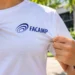 Pessoa segura camiseta branca com o logotipo da Facamp em área externa iluminada.