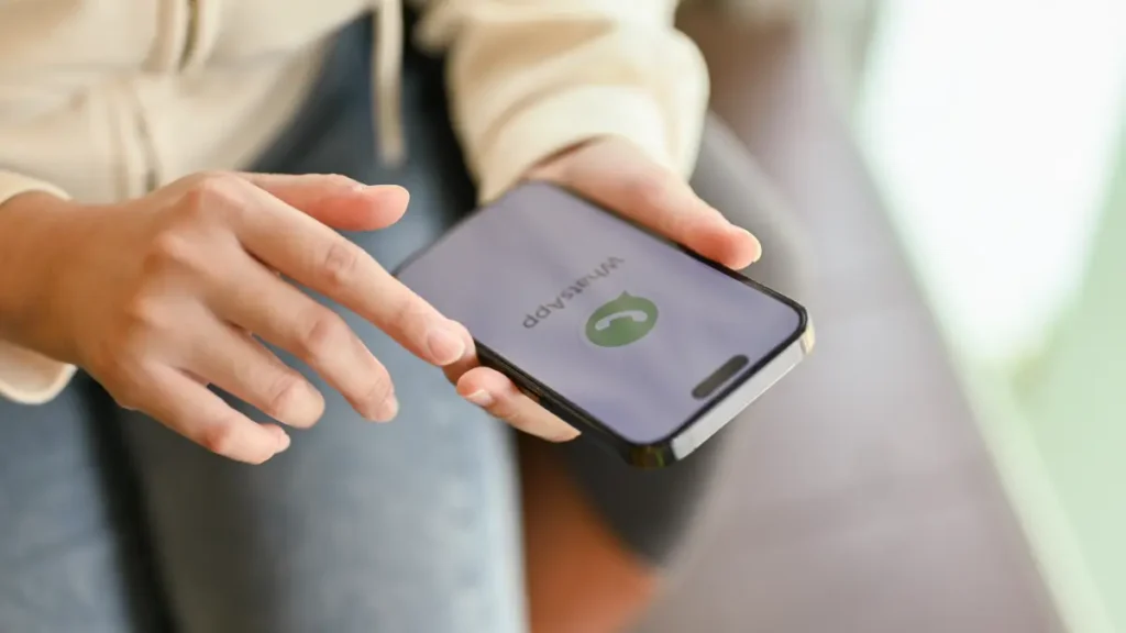Mãos segurando celular aberto em tela de WhatsApp.