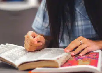 Mulher escreve à mão em folha de papel, tema do Acordo Ortográfico e das datas da nova grafia
