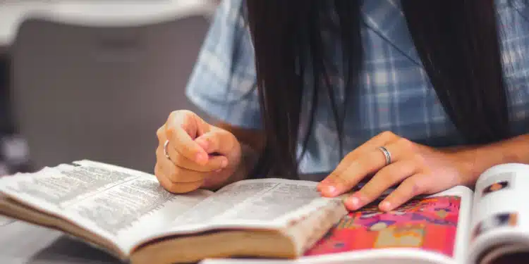 Mulher escreve à mão em folha de papel, tema do Acordo Ortográfico e das datas da nova grafia