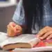 Mulher escreve à mão em folha de papel, tema do Acordo Ortográfico e das datas da nova grafia