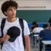 Estudante segura um boné nas mãos antes de entrar na sala de prova, representando as regras para o uso de chapéus e bonés durante o Enem.